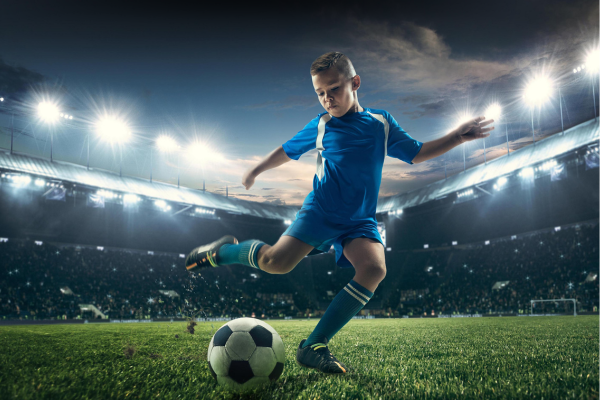 boy playing soccer in stadium under lights