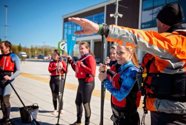 A group of people getting instructions from a watersports coach before they go onto a lake