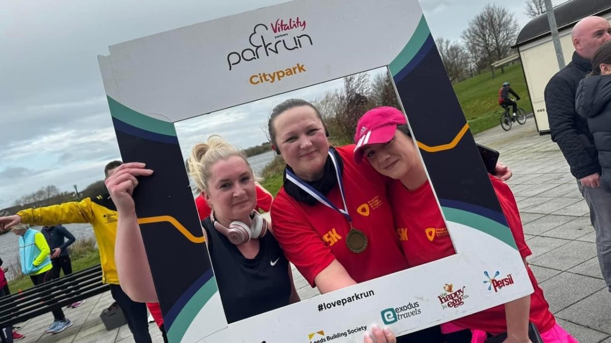 Three females wearing sports clothes having just completed the couch to 5k running programme. They are holding a social media frame.