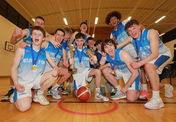 Team photo of male basketball players celebrating with a trophy.