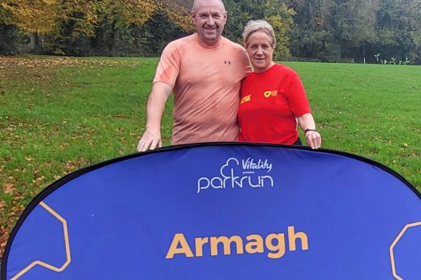 Man and woman standing behind an Armagh Parkrun sign